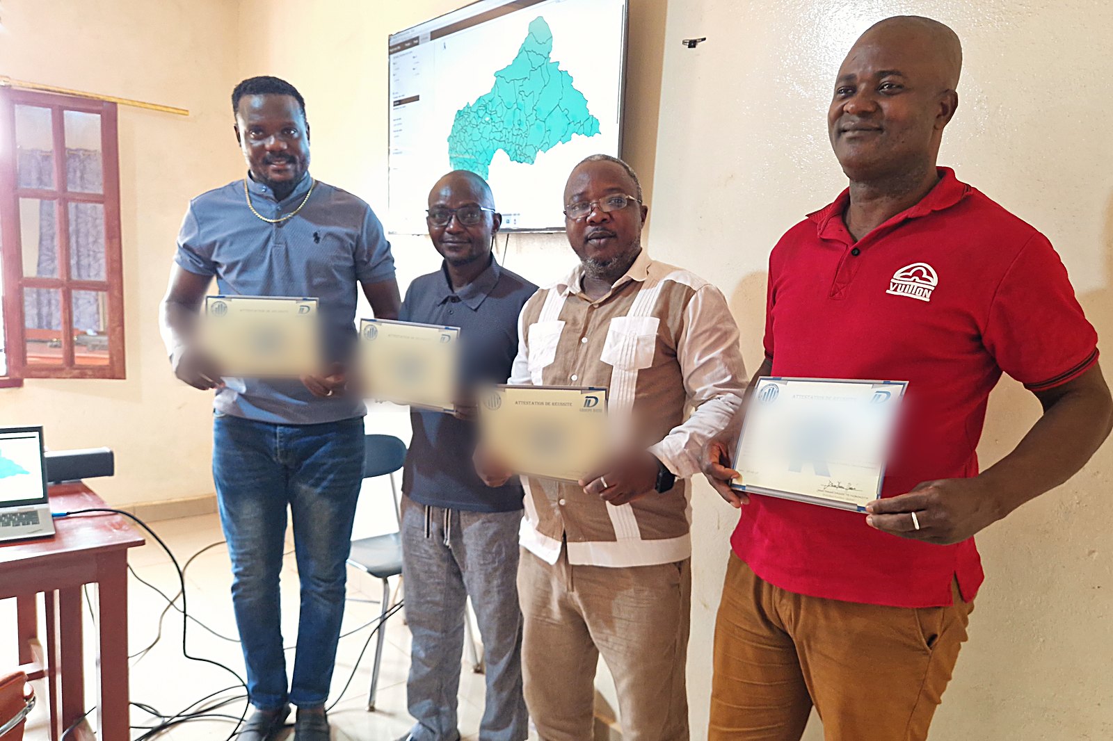 Quatre lauréats de la première promotion tenant leur attestation de réussite, Bangui, janvier 2026